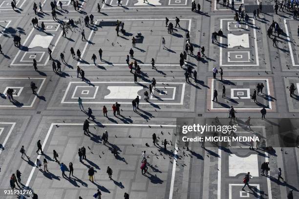 This picture taken from the roof of the Duomo in Milan on March 14, 2018 shows people walking across Duomo square. / AFP PHOTO / MIGUEL MEDINA
