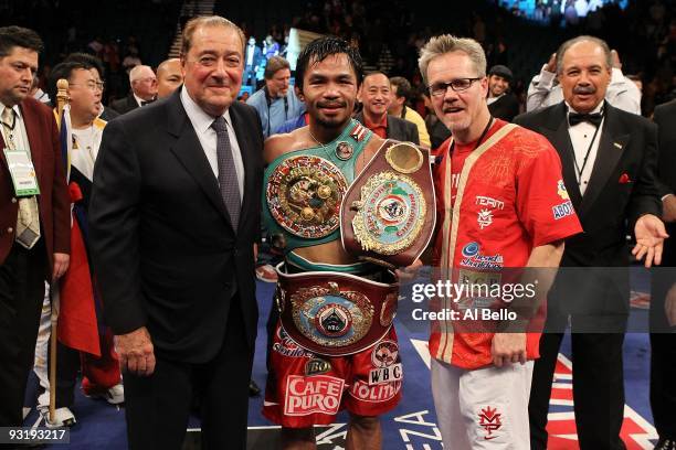 Promoter Bob Arum, boxer Manny Pacquiao and trainer Freddie Roach celebrate Pacquiao's 12 round TKO victory against Miguel Cotto during their WBO...