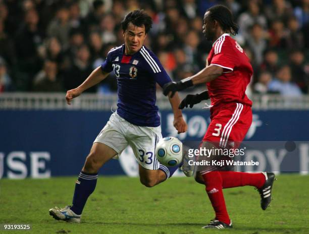 Shinji Okazaki of Japan and Gerard Ambassa Guy of Hong Kong compete for the ball during AFC Asia Cup 2011 Qatar qualifier match between Hong Kong and...