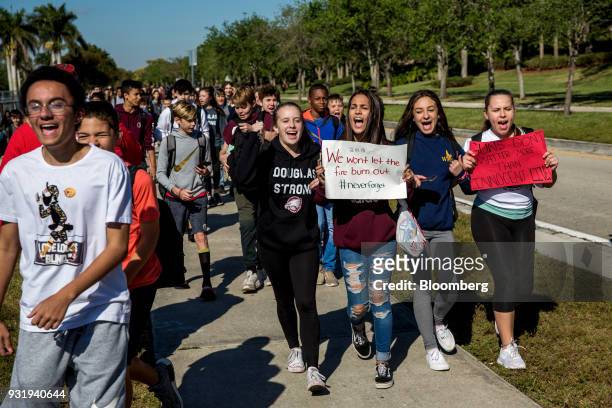 Students carry signs and chant while walking outside Marjory Stoneman Douglas High School during the ENOUGH: National School Walkout rally in...