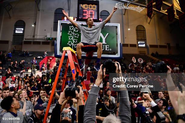 Darnell Foreman of the Pennsylvania Quakers sits atop the rim after the win at The Palestra on March 11, 2018 in Philadelphia, Pennsylvania. Penn...