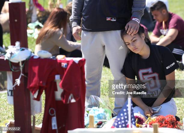 Gabriel Constantino and Nikki Healey from Marjory Stoneman Douglas High School stand together at a memorial after walking out of school to honor the...