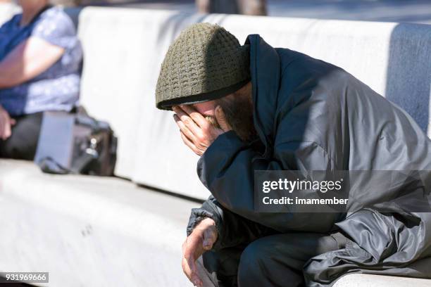 homeless man sitting on park bench, background with copy space - homeless man stock pictures, royalty-free photos & images