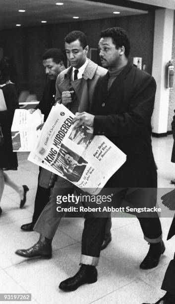 As he walks through O'Hare Airport, American Civil Righter leader and minister Jesse Jackson holds a copy of the Daily Defender newspaper, which...