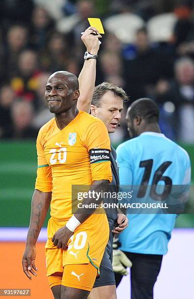 Referee Bjoern Kuipers shows a yellow card to Cote d'Ivoire defender Guy Demel, after a foul which yielded a penalty kick during the friendly...