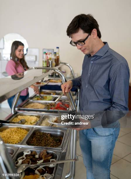 man serving food at a buffet restaurant - restaurant queue stock pictures, royalty-free photos & images