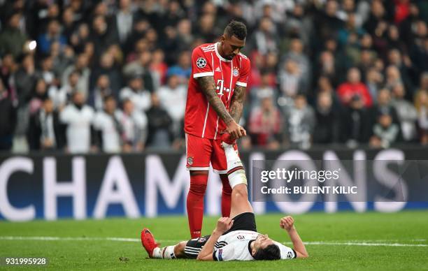 Bayern Munich's German defender Jerome Boateng helps Besiktas forward Mustafa Pektemek with cramping during the second leg of the last 16 UEFA...