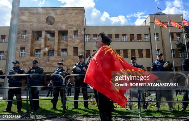 Woman wraps herself in a flag, protests next to a police cordon set in front of the parliament building in Skopje on March 14 against the law which...