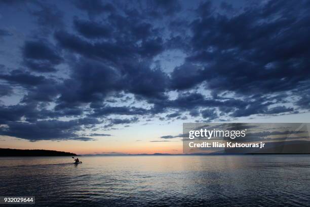 person kayaking in sea under cloudy sky - katsouras stock-fotos und bilder