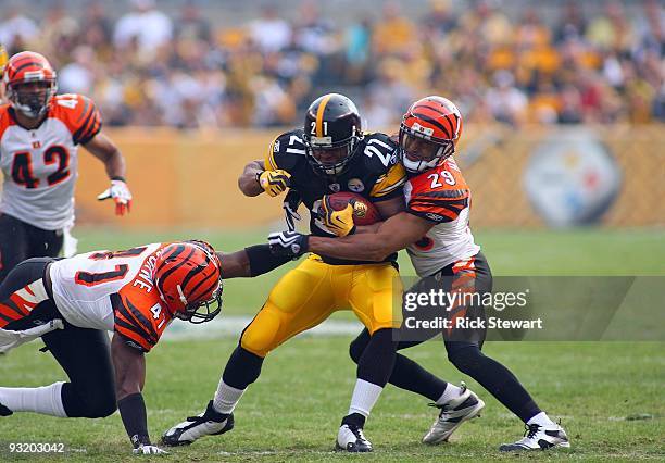 Mewelde Moore of the Pittsburgh Steelers runs with the ball against Chinedum Ndukwe and Leon Hall of the Cincinnati Bengals during their game at...