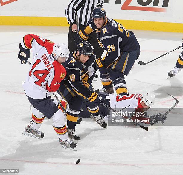 Radek Dvorak of the Florida Panthers and Tim Connolly of the Buffalo Sabres try to get control of the puck as Paul Gaustad of the Sabres defends on...