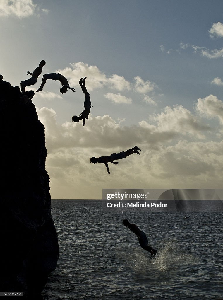 People jumping off a rock at Waimea Bay