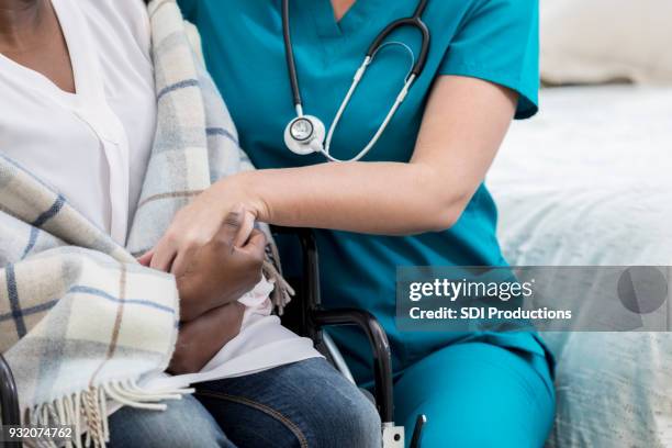 unrecognizable home healthcare nurse comforts senior patient - care home bed stock pictures, royalty-free photos & images