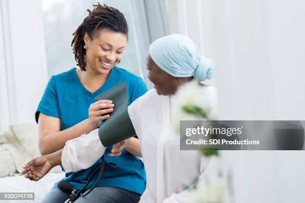 confident nurse checks patient's blood pressure - nurse hat stock pictures, royalty-free photos & images