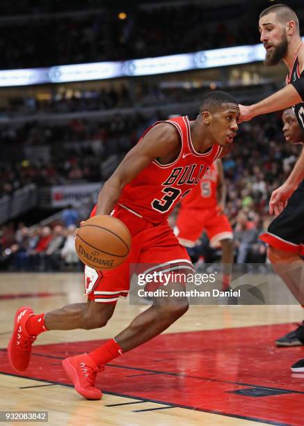 Kris Dunn of the Chicago Bulls drives against Jonas Valanciunas of the Toronto Raptors at the United Center on February 14, 2018 in Chicago,...