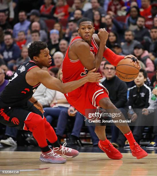 Kris Dunn of the Chicago Bulls drives around Kyle Lowry of the Toronto Raptors at the United Center on February 14, 2018 in Chicago, Illinois. The...