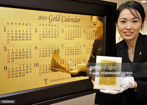An employee of Japan's jeweler Tanaka Kikinzoku Jewelry displays a 2010 calendar made of six-kilograms of pure gold and smaller sized calendar at the...