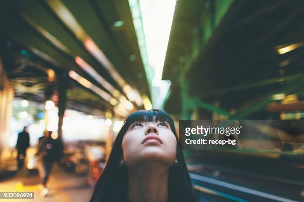 retrato de mujer mientras loo0king de cerca para arriba en la ciudad - differential focus fotografías e imágenes de stock