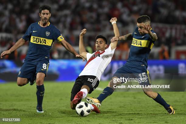 Argentina's River Plate player Gonzalo Martinez vies for the ball with Boca Juniors Pablo Perez and Nahitan Nandez during their Supercopa Argentina...