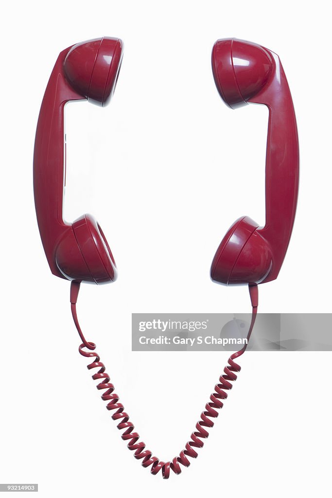 Two red phone handsets connected to same cord
