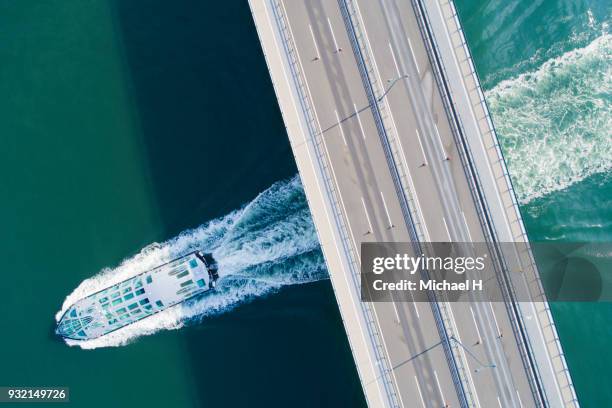 aerial view of a bridge and a ship at sea. - green boat stock pictures, royalty-free photos & images