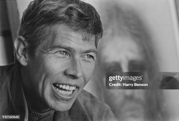 American actor James Coburn , 4th May 1966. In the background, a drawing of Jesus Christ by American actress and visual artist Kim Novak.