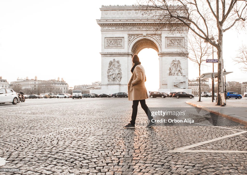 Hombre camina delante de Arc de Triomphe