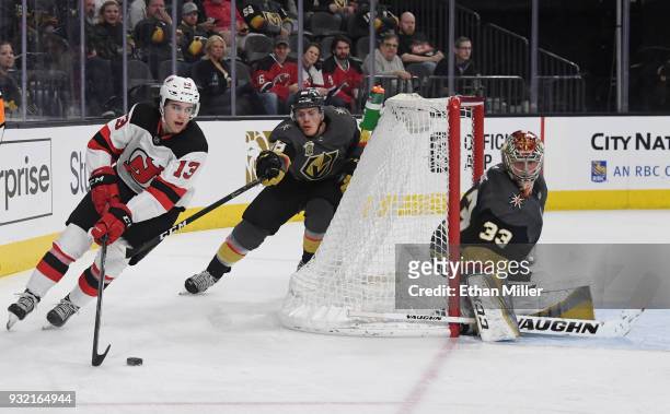 Nico Hischier of the New Jersey Devils skates with the puck against Nate Schmidt of the Vegas Golden Knights as Maxime Lagace tends net in the third...