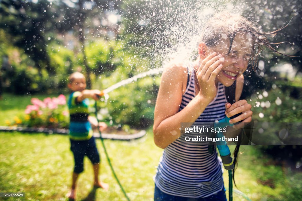 Kinderen met spatten van plezier in achtertuin