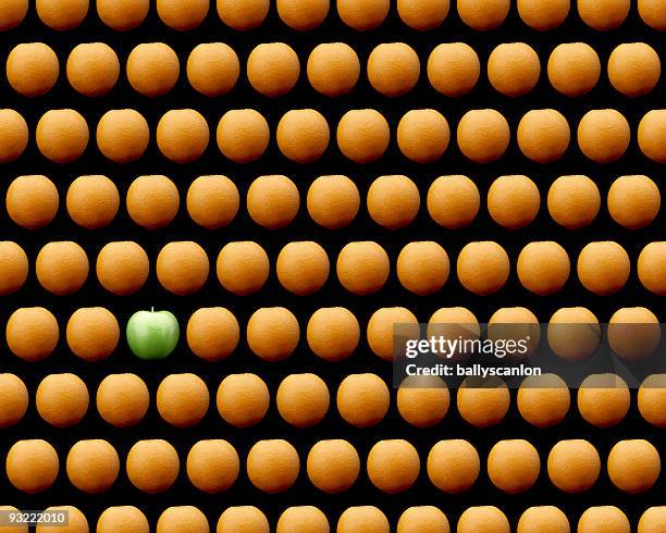 oranges and one granny smith on black background. - granny smith stock pictures, royalty-free photos & images