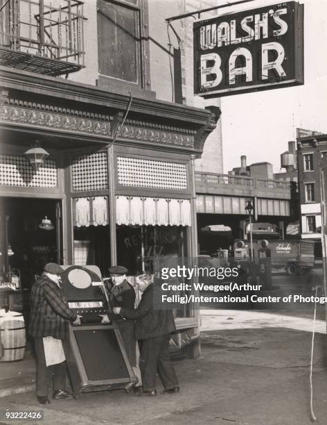 Men carry out a cigarette machine from Walsh's Bar and Grill, located at 213 Tenth Ave. In New York City, after the place was accused of taking bad...