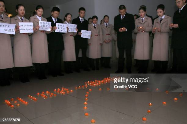 Students of Qingdao Aeronautical Vocational and Technical School holding candles bow during a commemorative activity following the death of world...