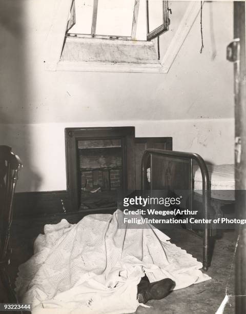 The dead body of an 11 year old boy lies covered by a blanket in an attic, near a bed and in front of an open closet door, New York, February 1944....