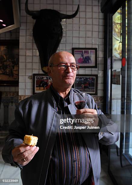 Seventy-three year old Pedro holds a glass of wine and a piece of tortilla de patatas in a bar on November 19, 2009 in the center of Madrid, Spain....