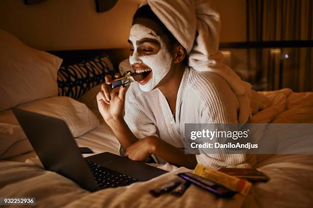 woman relaxing at home using laptop - eating chocolate stock pictures, royalty-free photos & images