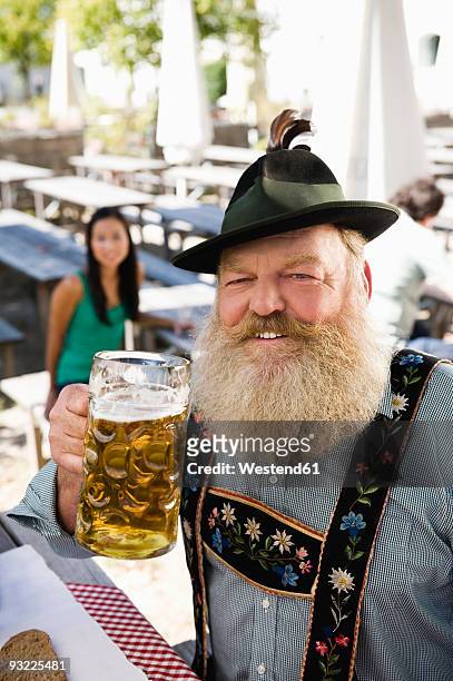 germany, bavaria, upper bavaria, senior man in beer garden holding beer stein, portrait - bierkrug stock-fotos und bilder