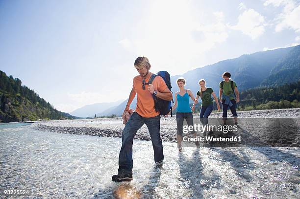 germany, bavaria, tölzer land, young friends walking through river - knöcheltief im wasser stock-fotos und bilder