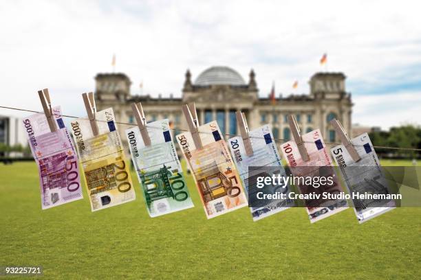 germany, berlin, euro bank notes hanging on clothesline, reichstag building in background - money laundering stock pictures, royalty-free photos & images
