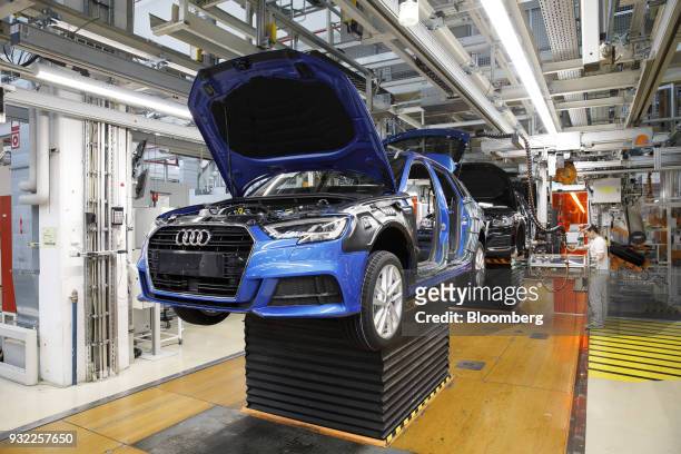An Audi A3 automobile stands on an hydraulic platform on the wheel fitting assembly line inside the Audi AG headquarter factory in Ingolstadt,...