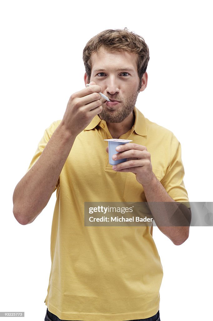 Young man eating Yoghurt, portrait