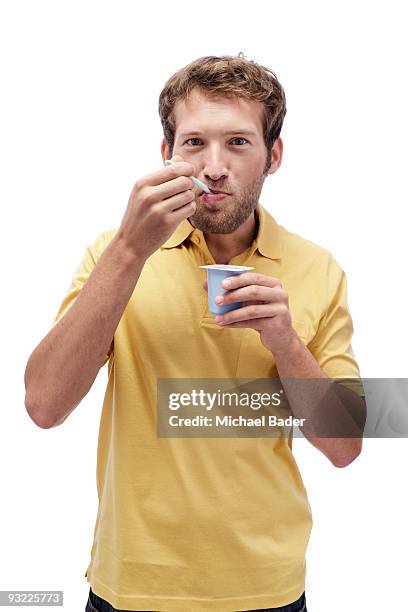 young man eating yoghurt, portrait - indulgence white background stockfoto's en -beelden