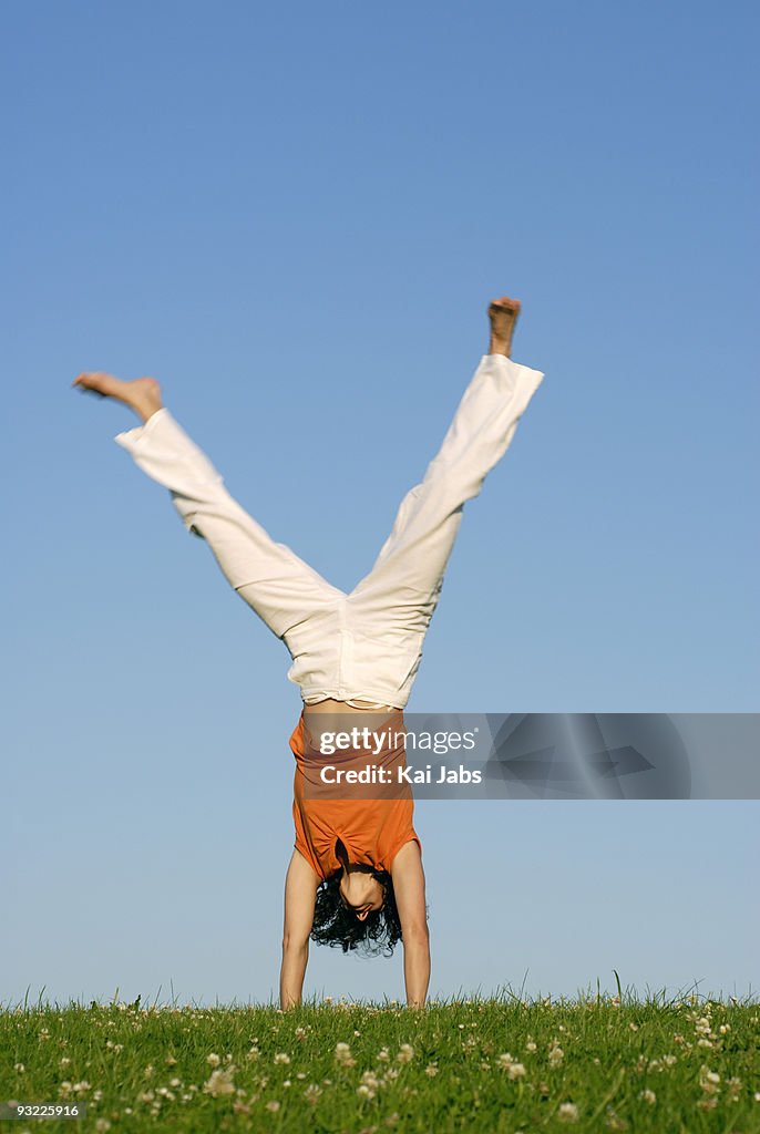 Young woman doing handstand on meadow