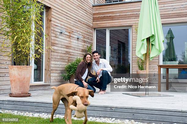 germany, bavaria, munich, couple on terrace in front of house with dog - bavarian man in front of house stockfoto's en -beelden