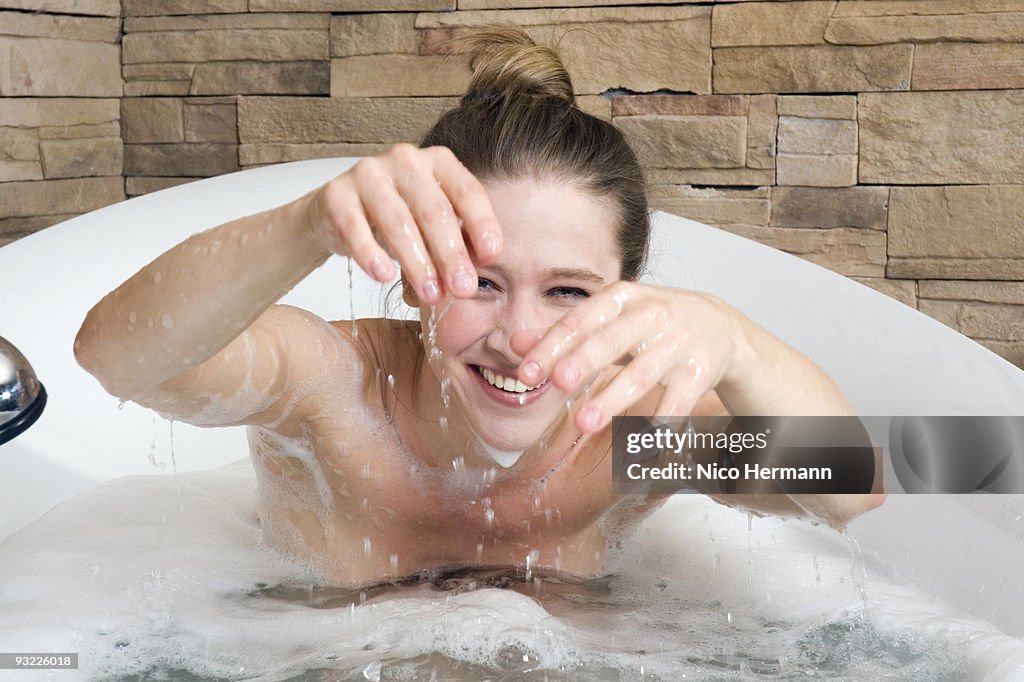 Young woman in bathtub fooling about