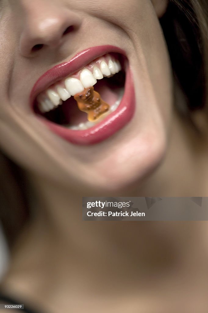 Young woman with gummi bear in mouth, portrait