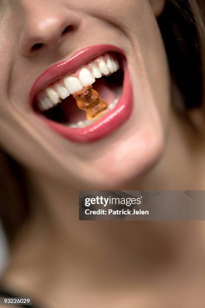 young woman with gummi bear in mouth, portrait - gummi bears stockfoto's en -beelden