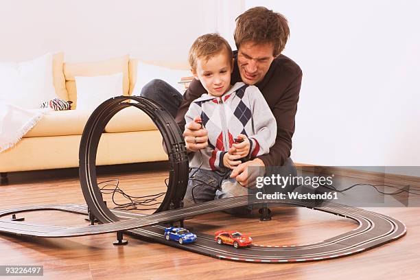 father and son (4-5) playing with toy racetrack - auto sofa stock-fotos und bilder