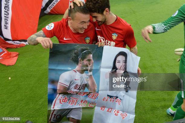This picture taken on March 14, 2018 shows Alexandre Pato of Tianjin Quanjian , holding a poster showing pictures of him and Chinese actress Dilraba...