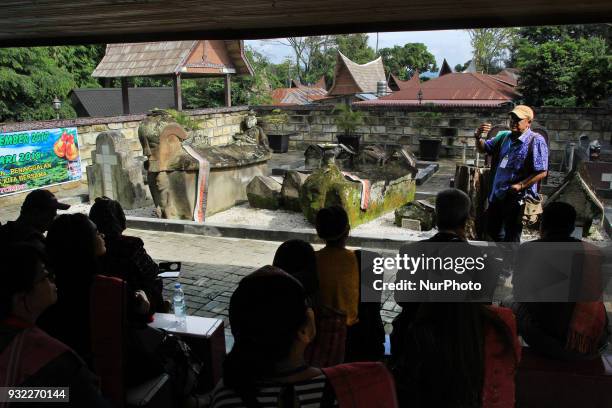 Tour guide was explaining to the tourists about the ancestral tomb of King Sidabutar on Samosir Island. Lake Toba is the largest volcanic lake in...
