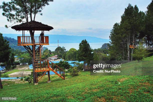 Tourist is looking at the view of Lake Toba from the top of the view tower. Lake Toba is the largest volcanic lake in Southeast Asia. The lake is...